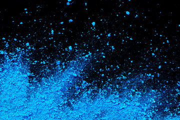 Blue color background of chalk powder. Blue color dust particles splattered on black background.