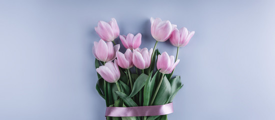 Bouquet of Pink tulips flowers over light blue background. Greeting card or wedding invitation. Flat lay, top view, copy space. Wide composition