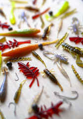 Fototapeta na wymiar Colorful silicone fishing baits with plummets on wooden table. Various fish and worms and crayfish. Toned image and top view. Stock background, photo