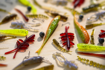 Colorful silicone fishing baits with plummets on wooden table. Various fish and worms and crayfish. Toned image and top view. Stock background, photo