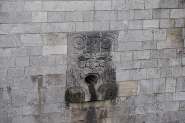 stone face scuplture in stone wall water stream