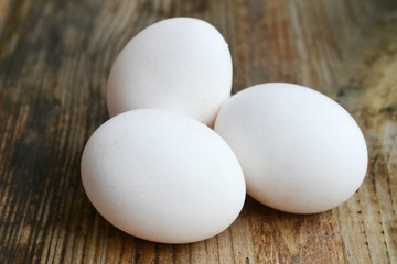 Three white eggs on wooden table