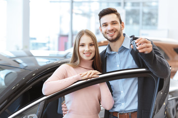 Beautiful happy couple holding keys of their newly bought car