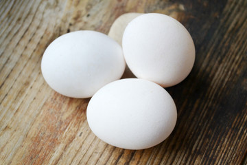 Three white eggs on wooden table