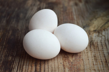 Three white eggs on wooden table