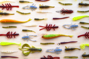 Colorful silicone fishing baits with plummets on wooden table. Various fish and worms and crayfish....