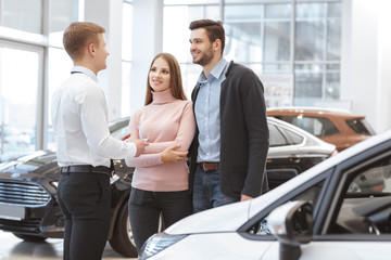 Young couple choosing a car with salesman at the dealership