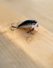 Colorful fishing baits with plummets on wooden table. Wobbler on a wooden board with beautiful eyes. Toned image and top view. Stock background, photo
