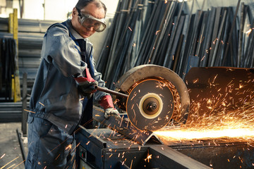 Industrial worker cutting metal at the factory