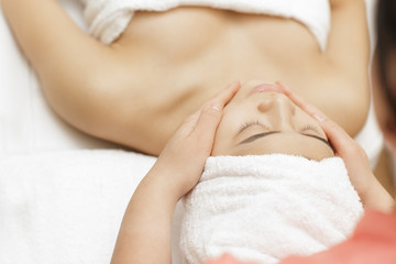 Obraz na płótnie Canvas Young Asian female receiving facial massage by a professional beautician