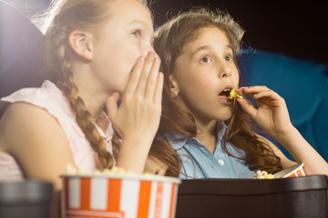 Kids whispering while watching a film at the cinema