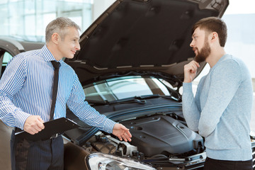 Handsome young man buying car from a professional dealer