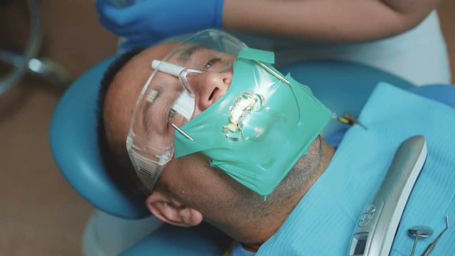 Portrait of patient with cofferdam in mouth in dental cabinet. 4K