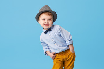 Portrait of happy joyful  little boy isolated on blue background. Toddler child in hat and...