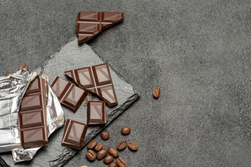 dark chocolate bar and pieces on dark concrete background