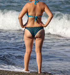 Obraz premium Booty girl in a swimsuit on the beach of the sea