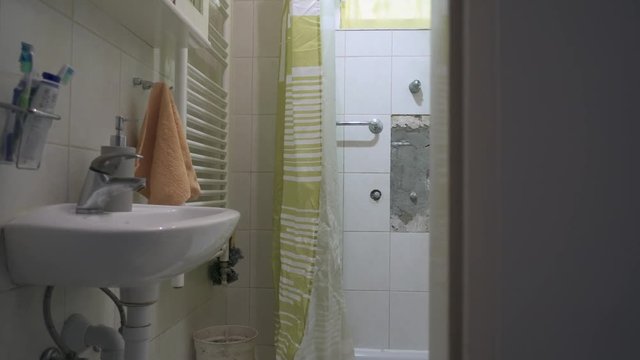 Camera slides and revealing the bathroom, missing faucet and tiles, visible water pipes in the wall, a slider movement.