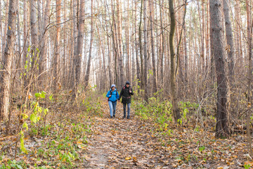 Fototapeta premium Travel, tourism, hike and people concept - tourists couple in autumn forest