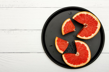 Grapefruit in a black dish on a white wooden table. Grapefruit on a white wooden table.