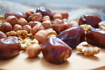 Delicious and healthy nuts and dates on burlap,on a wooden background.