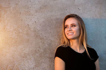 Horizontal portrait of beautiful smiling blonde woman on outdoor wall background with copyspace.