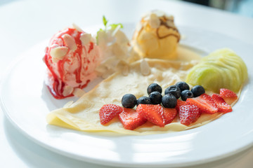 Fruity Crepe Ice Cream with scoops of  vanilla and strawberry on white plate.