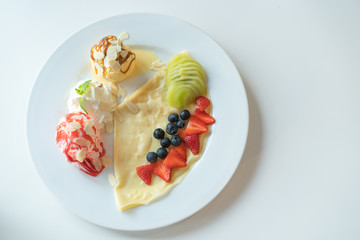Fruity Crepe Ice Cream with scoops of  vanilla and strawberry on white plate.