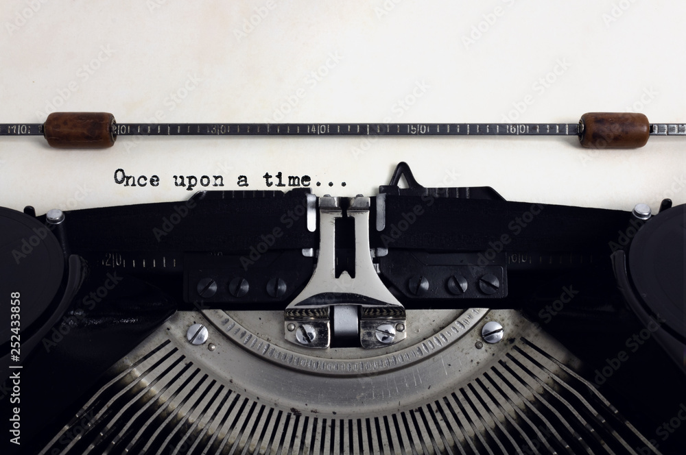 Fototapete old retro vintage black typewriter with close-up typing text once upon a time as heading on aged pap