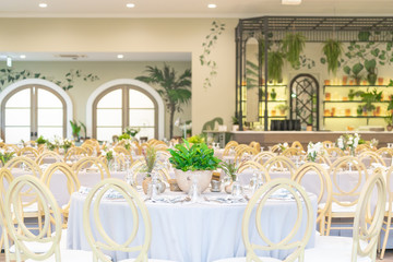 Wide shot of setting of tables for Wedding celebration dinner with a white bouquet and beautiful flower.
