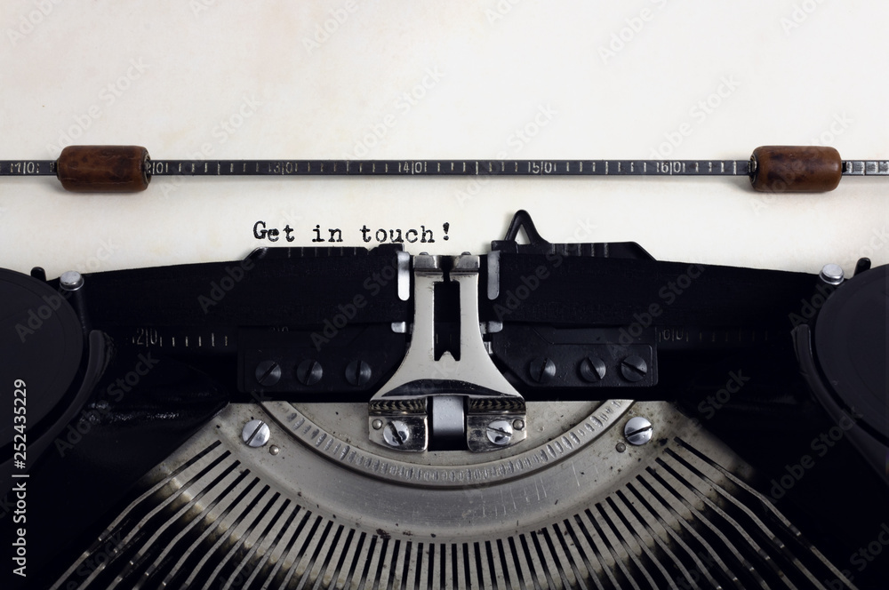 Fototapete old retro vintage black typewriter with close-up typing text get in touch as heading on aged paper