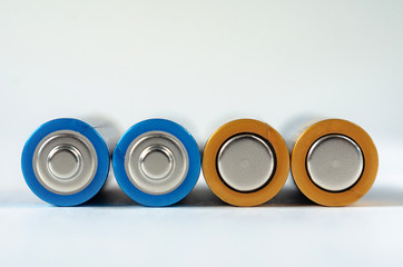 Four blue-golden AA batteries close-up on a white background. shallow depth of field, macro