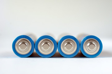 Four blue-golden AA batteries close-up on a white background. shallow depth of field, macro