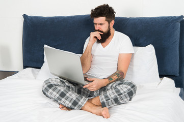 Freelance job. Stay in bed and keep working. Freelance benefits. Man surfing internet or working online. Hipster bearded guy pajamas freelance worker. Remote work concept. Online search job position