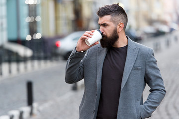Delicious drink. Man bearded hipster drink coffee paper cup. Businessman well groomed enjoy coffee break outdoors urban background. Prefer coffee on the go. Thoughtful but relaxed. Take self care