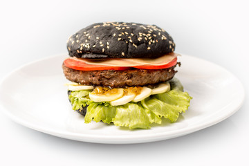 cheeseburger with black bread, beef cutlet, bacon, tomatoes and cheese slices, seasoned with sauce and green salad for a restaurant menu on a white isolated background