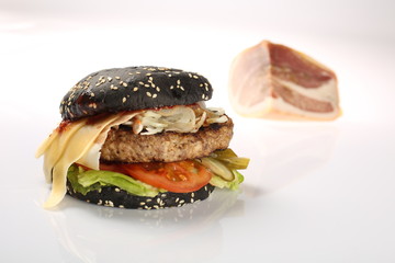 cheeseburger with black bread, beef cutlet, bacon, tomatoes and cheese slices, seasoned with sauce and green salad for a restaurant menu on a white isolated background