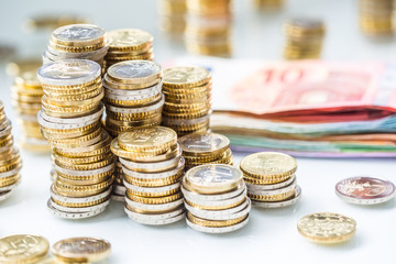 Euro banknotes and coins togetger on white table - close-up