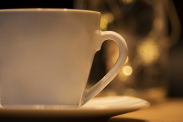 Eine Tasse mit Untersetzer mit einem romantischen Lichter Bokeh 