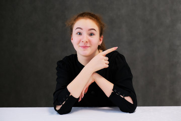 Concept portrait of a cute pretty teenager girl with red hair on a gray background smiling and talking.