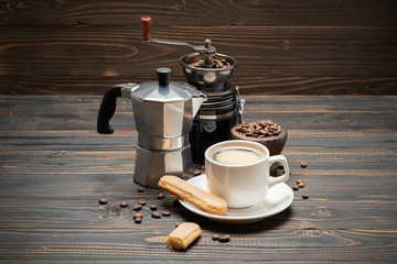 Cup of coffee with coffe maker on wooden backround