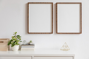 Stylish white home decor of interior with two brown wooden mock up photo frames with books,...