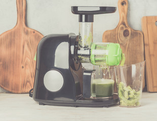 Slow masticating juicer producing healthy celery juice, extracting the pulp, on white table, healthy detox concept, selective focus