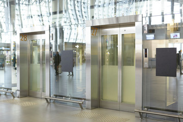 Two clean neat elevator in modern airport terminal or railway depot station with glass walls and...