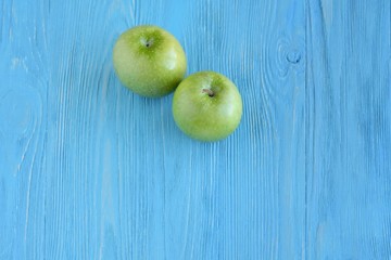 Juicy green organic apples with selective focus on textured blue wooden background. Green diet vegetarian ingredients. Healthy natural food for weight loss 