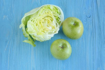 Juicy green organic apples with half of fresh lettuce with selective focus on blurred blue wooden background. Green diet vegetarian ingredients. Healthy natural food for weight loss 