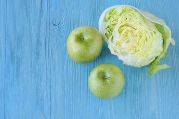 Juicy green organic apples with half of fresh lettuce with selective focus on blurred blue wooden background. Green diet vegetarian ingredients. Healthy natural food for weight loss 