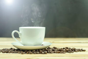 Cup of coffee with coffee beans on wood background.