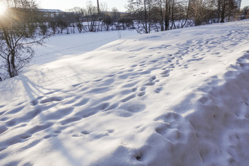 Snow drifts and footprints in the snow. Sunny day. Winter background.