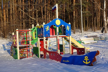 Empty playground for children on a frosty snowy winter day covered with snow without people. Russian playground. Maritime military theme. Raising children in the military spirit.