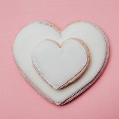 Two big and small heart shaped white cookie on a pink background. Love or like concept. Minimal food. Square image.